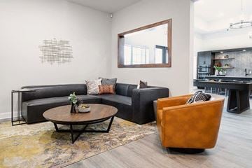 Killeen apartment for rent - A living room with a black couch, a brown leather chair, and a coffee table with a vase of flowers on it.