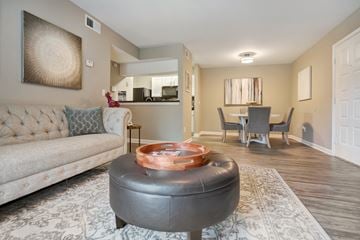 Jacksonville apartment for rent - A living room with a grey ottoman and a grey couch with a wooden coffee table in front of it.