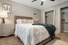 Jacksonville apartment for rent - A bedroom with a white bed and a green throw blanket.