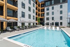 Atlanta apartment for rent - A swimming pool in front of a modern building with lounge chairs and umbrellas.