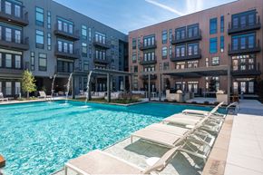 Dallas apartment for rent - a swimming pool with lounge chairs in front of an apartment building