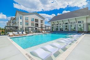 Houston apartment for rent - A pool with lounge chairs and a building in the background.
