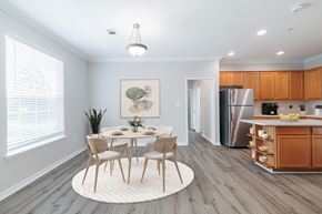 Conroe apartment for rent - A dining room with a table set for four and a kitchen in the background.