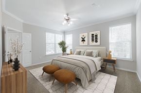 Conroe apartment for rent - A bedroom with a large bed, a wooden table, and a ceiling fan.