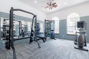 Conroe apartment for rent - A gym with a variety of equipment including a squat rack, a leg press machine, and a treadmill.