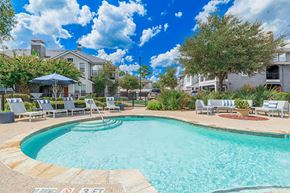 Conroe apartment for rent - A swimming pool surrounded by lounge chairs and umbrellas.
