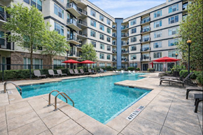 Atlanta apartment for rent - A pool surrounded by chairs and umbrellas in front of apartment buildings.