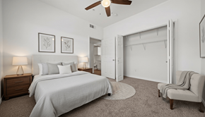 New Braunfels apartment for rent - A bedroom with a large bed, a chair, and a ceiling fan.