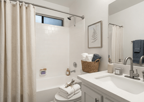 Riverside apartment for rent - A bathroom with a white tub, sink, and shower curtain.