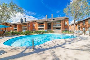 Webster apartment for rent - A large swimming pool in front of a red brick building.