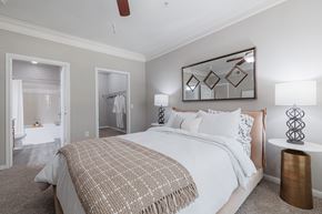 Houston apartment for rent - A bedroom with a large bed and a mirror on the wall.
