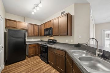 Waco apartment for rent - A kitchen with wooden cabinets and a black refrigerator.
