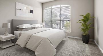 Dallas apartment for rent - A bedroom with a large bed, a nightstand with a lamp, and a potted plant.