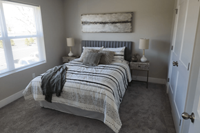 South Lyon apartment for rent - A bedroom with a bed, two lamps, and a painting on the wall.