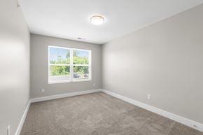 South Lyon apartment for rent - A room with a carpeted floor and a window showing a view of trees.