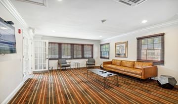 Rolling Meadows apartment for rent - A living room with a striped carpet and a brown couch.