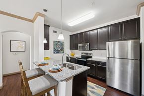 Conroe apartment for rent - A kitchen with a stainless steel refrigerator and a dining table with chairs.