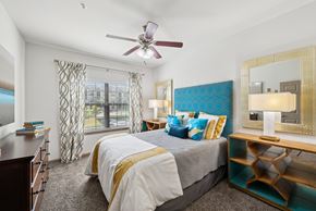 Conroe apartment for rent - A bedroom with a large bed and a ceiling fan.