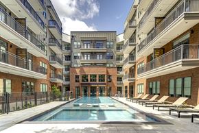 Austin apartment for rent - A large swimming pool in the middle of a courtyard surrounded by apartment buildings.
