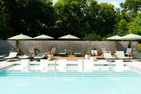 Nashville apartment for rent - A pool with chairs and umbrellas in the foreground and trees in the background.