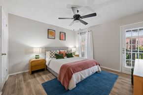 Dallas apartment for rent - A bedroom with a bed, a ceiling fan, and a window with blinds.