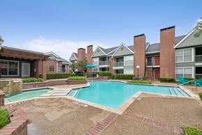Dallas apartment for rent - A swimming pool surrounded by brick and tile walkways in front of apartment buildings.