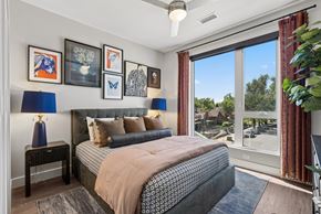 Denver apartment for rent - A bedroom with a large bed and a view of the outdoors through the window.