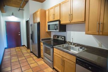 Spartanburg apartment for rent - A kitchen with brown cabinets and a black fridge.