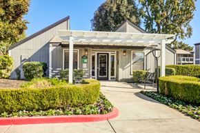 Sacramento apartment for rent - A building with a white canopy and a red border around the bushes.