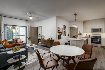 Apopka apartment for rent - A modern living room with a grey couch, a white coffee table, and a dining table with chairs.