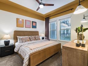 Houston apartment for rent - A bedroom with a bed, nightstand, and a ceiling fan.