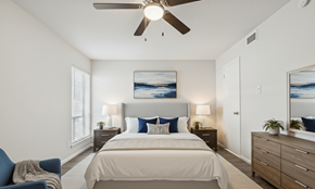 Austin apartment for rent - A bedroom with a bed, a chair, and a ceiling fan.