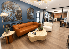 Miami Lakes apartment for rent - A modern living room with a brown leather sofa, a wooden coffee table, and a large abstract painting on the wall.
