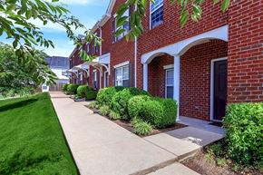 Spring Hill townhouse for rent - A row of red brick houses with green bushes in front.