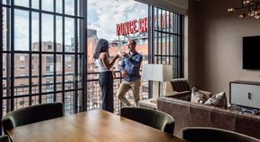 Atlanta apartment for rent - A man and woman standing in a room with a large window that has a view of a building with the word "Ponce" on it.
