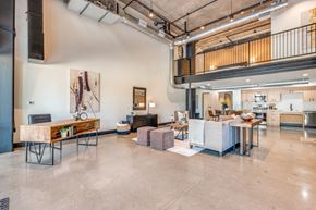Dallas apartment for rent - A large open space with a table and chairs in the foreground and a balcony with a railing in the background.