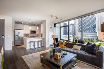 Chicago apartment for rent - A modern living room with a black leather couch and a coffee table in the center.