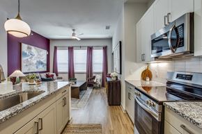 Fort Worth apartment for rent - A kitchen with a purple wall and a stove top oven.
