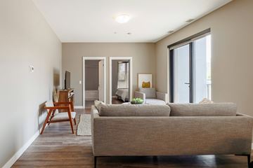 Raleigh apartment for rent - A living room with a grey couch and a wooden chair.