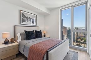 San Diego apartment for rent - A bedroom with a large bed and a view of the city.