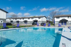 Stephenville apartment for rent - A swimming pool with blue chairs and a white building in the background.