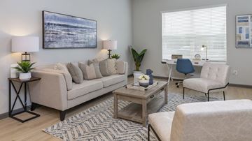 Jacksonville apartment for rent - A living room with a beige sofa, a coffee table, and a painting on the wall.