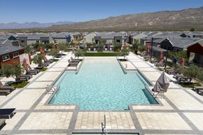 Tucson apartment for rent - A large swimming pool surrounded by lounge chairs and umbrellas in a residential area.