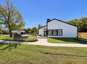 Moore apartment for rent - A modern white house with a black roof and a black chimney is surrounded by a green lawn and trees.