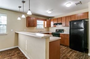 Hobbs townhouse for rent - A kitchen with a black refrigerator and wooden cabinets.