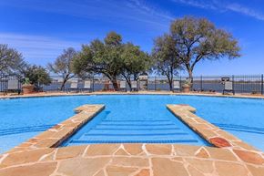 Granbury apartment for rent - A swimming pool with a stone border and steps leading into the water.