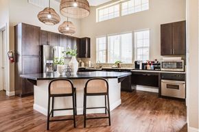 Bryan apartment for rent - A kitchen with a black refrigerator and wooden floors.
