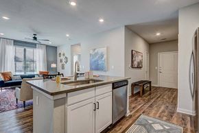 Conroe apartment for rent - A kitchen with a large island and a refrigerator on the right.