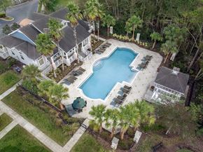 Jacksonville apartment for rent - A large swimming pool surrounded by a white fence and palm trees.