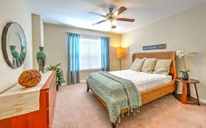 Jacksonville apartment for rent - A bedroom with a bed, a ceiling fan, and a mirror on the wall.